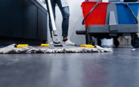 Low shot of cleaning lady mopping the floor in restroom beside her trolley