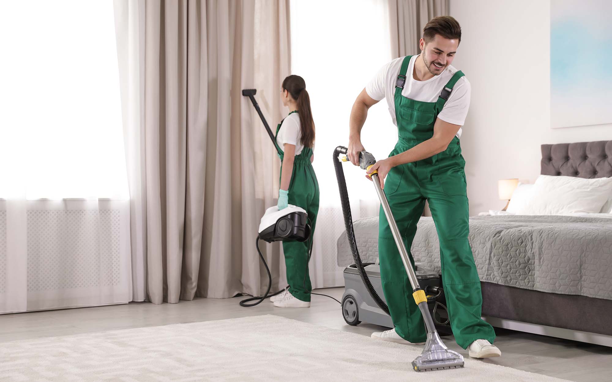 Team of janitors cleaning bedroom with professional equipment_