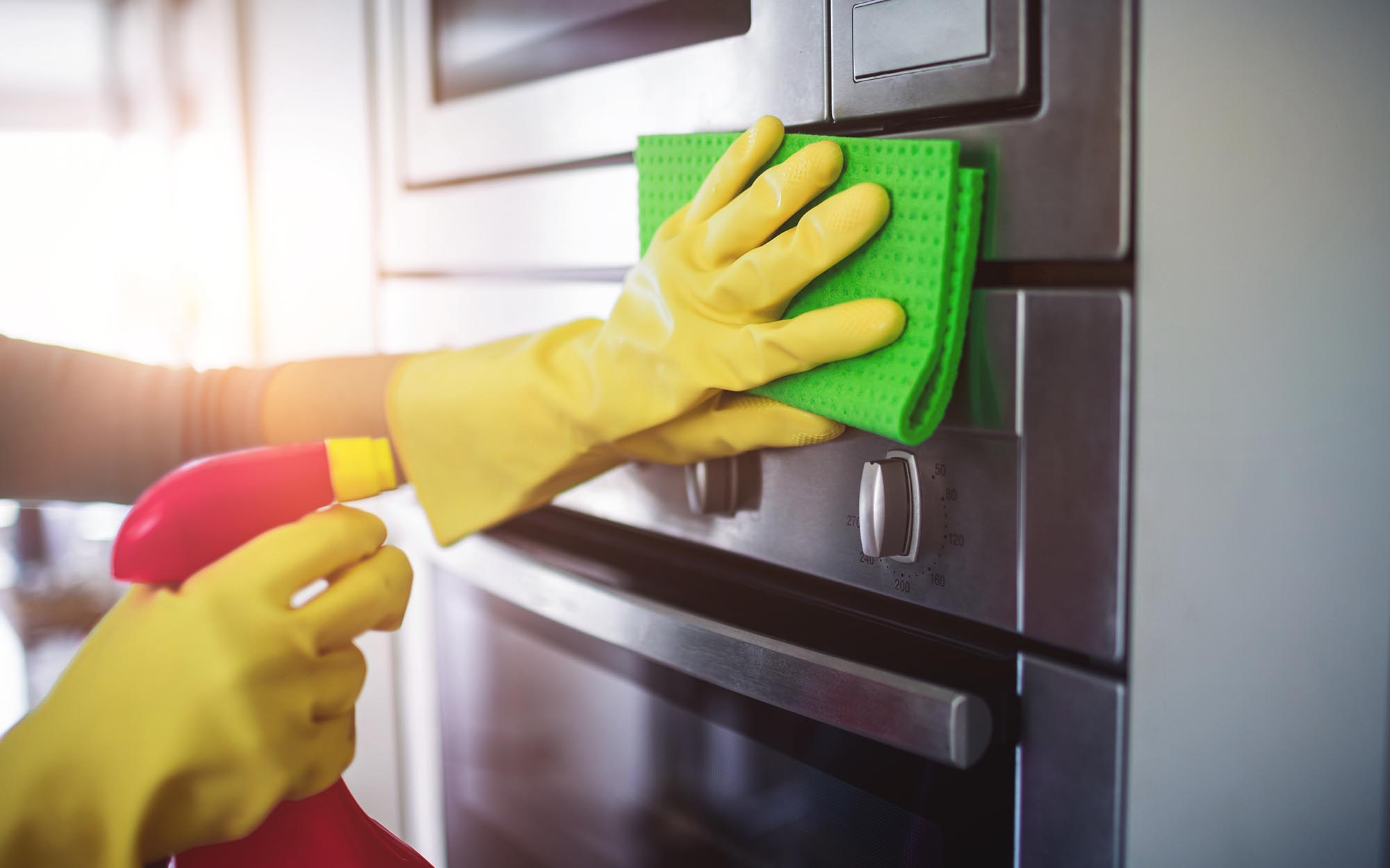 Image of a person wiping down their microwave at home.